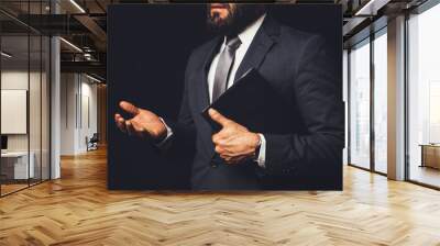 man in suit holding a bible in his arm speaking to another person on a black background Wall mural