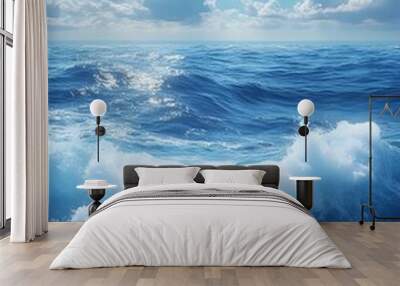 A serene view of the ocean waves with bright blue water and fluffy white clouds scattered across the sky, creating a tranquil seaside atmosphere. Wall mural