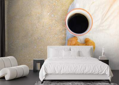 Black coffee and croissant on sand background, breakfast on the beach, food and drink concept. Wall mural