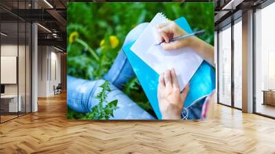 teenage girl student writing in notebook in park. Preparation for exams at college or university Wall mural