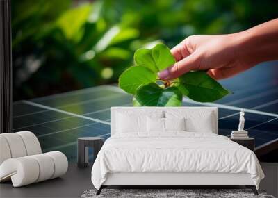 Conceptual representation of clean sustainable energy production with a hand holding green leafs over a solar panel. Wall mural