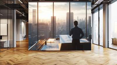 A professional gazes at a city skyline during sunset, reflecting on future plans and opportunities in a modern office. Wall mural