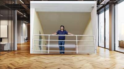 Hispanic man looking from a second floor , low angle view Wall mural