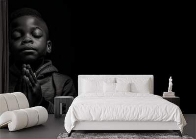 Black and white studio portrait of a young child praying banner on black background Wall mural