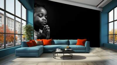 Black and white studio portrait of a young child praying banner on black background Wall mural