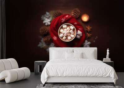 A mug of hot chocolate with marshmallows sits on a wooden table surrounded by pinecones, a red scarf, and a lit candle. Wall mural