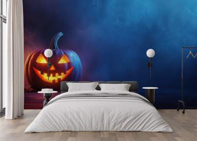 A halloween lit Jack O Lantern in a spotlight glow on a wide dark blue background Wall mural