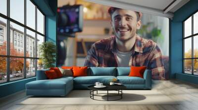 Smiling Man Being Interviewed on Camera. Cheerful man in a casual shirt sitting for an on-camera interview in a cozy room, giving a sense of approachability and openness. Wall mural