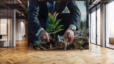 A business leader planting a tree in a deforested area, showing personal commitment to environmental restoration Wall mural