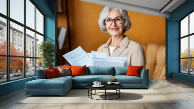 A businesswoman grandmother, smiling and holding a document, poses in a casual, indoor portrait. Wall mural