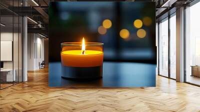 A close-up of a lit candle on a black table with a blurred background Wall mural