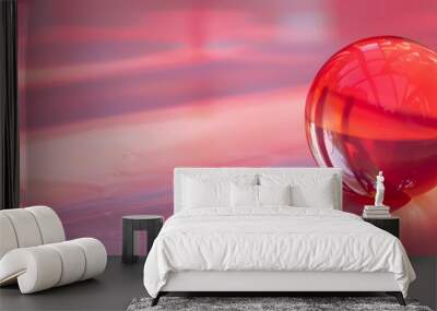 a close up of a red object on a pink surface with a reflection of the object in the middle of the image and the light reflecting off of the object. Wall mural