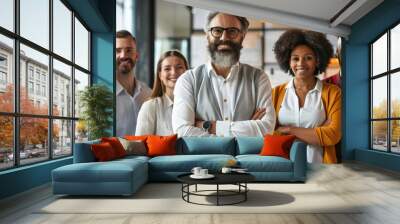 A diverse and smiling business team led by a confident chief stands together indoors. Wall mural