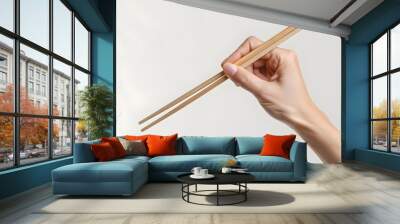 A hand holding wooden chopsticks isolated on a plain background AI Wall mural