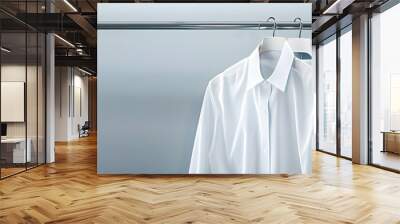 A hanger displaying a white long sleeved men s shirt and two gray suits provides a copy space image Wall mural