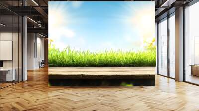 A natural spring garden background of fresh green grass with a bright blue sunny sky with a wooden table to place cut out products on. Wall mural