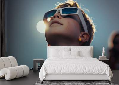 A young boy safely looks at a total eclipse while wearing protective glasses. Wall mural