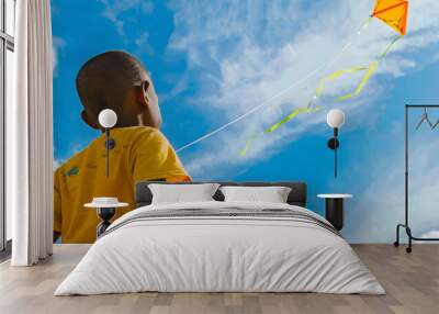 African american boy enjoying kite flying against blue sky on sunny day Wall mural