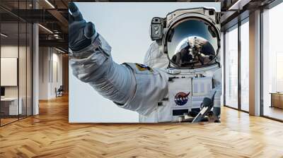 An astronaut reaching out towards the viewer against a clear sky backdrop, symbolizing connection and exploration Wall mural