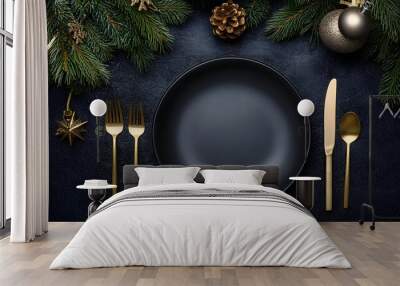 Christmas table setting with empty black ceramic plate, fir tree branch and gold accessories on black stone background. Top view. Copy space Wall mural