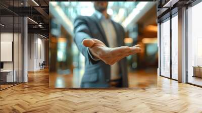 Close-up of a businessman extending his hand for a handshake in a modern office lobby. Wall mural