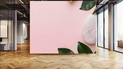 Composition of white mockup serum bottle, pink quarts stone face roller and gua sha stone with fresh leaves on pink background. Natural cosmetics concept. Creative cosmetics web banner flat lay    Wall mural