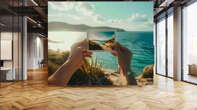 Hands holding polaroid photo up to seaside travel destination Wall mural