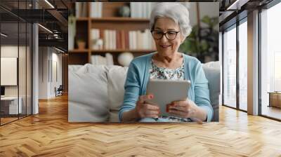 Happy pretty elder woman using digital tablet computer at home, reading electronic book, talking on video call, enjoying online communication, domestic Internet technology Wall mural