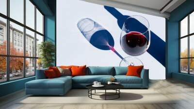 Glass and bottle of red wine on white with hard light. Wall mural