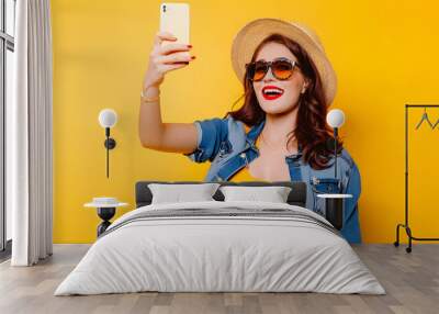 Portrait of cool cheerful girl having video-call with lover holding smart phone in hand shooting selfie on front camera isolated on yellow background enjoying weekend vacation Wall mural