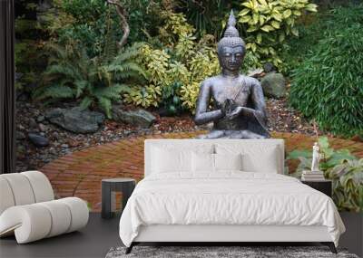 Seated Buddha statue on a round brick patio amid lush green garden Wall mural