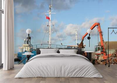 Ship being loaded with steel scrap by a crane, portrait view Wall mural