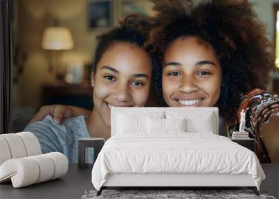 Smiling biracial teen daughter taking selfie with mother over smartphone at home, copy space Wall mural