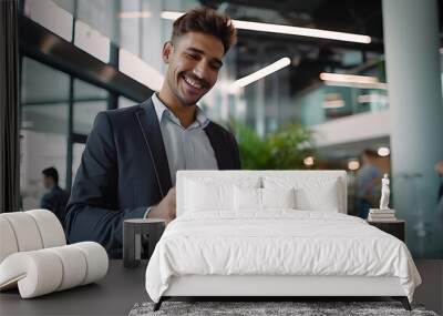 Smiling busy young Latin business man entrepreneur using tablet standing in office at work. Happy male professional executive manager using tab computer managing financial banking or marketing data Wall mural