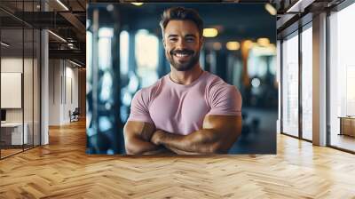 Smiling male personal trainer pink t shirt portrait of smiling at camera in gym. Happy man fitness coach standing in modern sport club interior. Active sport life getting fit healthy lifestyle concept Wall mural