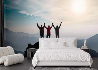 Together overcoming obstacles with three people holding hands up in the air on mountain top , celebrating success and achievements Wall mural