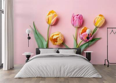 A flat lay of five vibrant tulips in shades of pink and yellow, isolated on a harmonious monochromatic pink background Wall mural