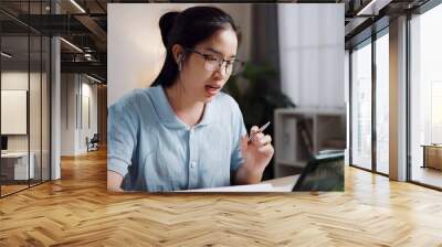 Portrait of Female freelancer sitting at desk wear wireless headphones having video call to explain work to coworkers via digital tablet in home office. Working from home Wall mural