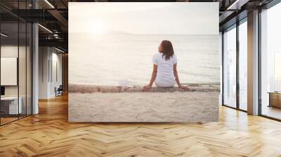 Rear of young woman sit on dead wood on the beach. Freedom enjoy Wall mural