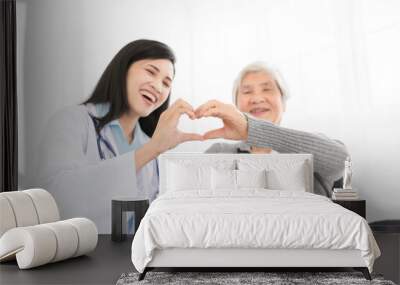 asian female doctor and old patient show heart sign with hand, happiness and relationship in hospital, they feeling happy and smile on white background Wall mural