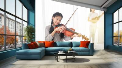 close up asian children holding violin on her shoulder, she play violin in classroom, she show violin skill and present melody with her friend, couple asian children in musical training time Wall mural