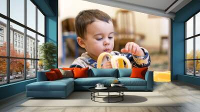 Funny boy 2 years old eating banana. Funny boy 2 years old eating banana Wall mural