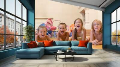 The group of four children lying on the floor. Four happy children lie on the floor. Wall mural