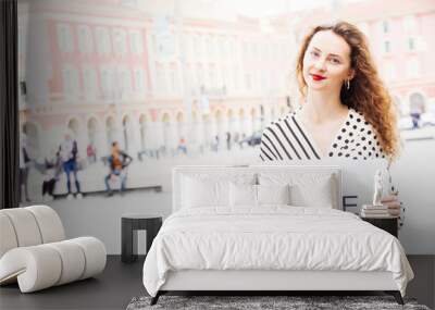 Red hair young French caucasian girl is traveling in nice  capital of french river and hold a paper with the hashtag Nice Wall mural