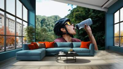 A young female cyclist drinking water from her water bottle Wall mural