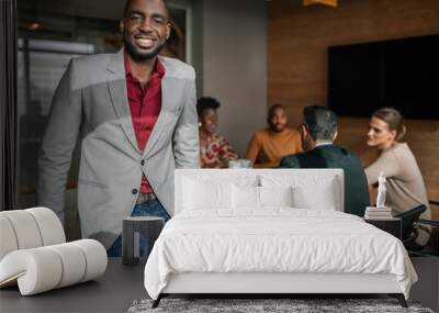 Casual portrait of professional black african business man, coworkers hold a meeting in background Wall mural