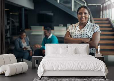 portrait of a confident black businesswoman smiling with her arms crossed and all african team in th Wall mural