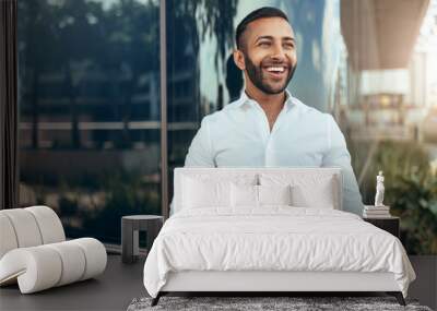 Portrait of a young confident smiling indian man holding a tablet and looking into the distance Wall mural