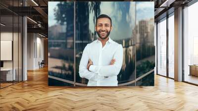 Portrait of a young confident smiling indian man with his arms crossed looking into the camera Wall mural