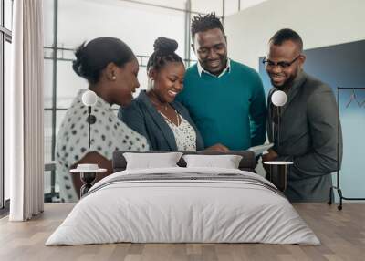 Team of african business people standing and smiling and laughing while using a tablet Wall mural